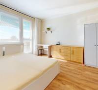 Helles Schlafzimmer in einer Einzimmerwohnung mit Holzboden, Schrank und Bett.