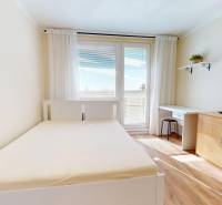 Ein Zimmer mit Bett, Schreibtisch und Stauraum in einer Einzimmerwohnung.
