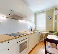 Küche in einer Einzimmerwohnung mit weißen Schränken und einem Boden in Holzoptik.
