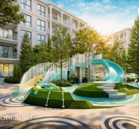 Spielplatz bei einem Wohnungsbauprojekt in Phuket mit großer Rutsche und viel Grün.