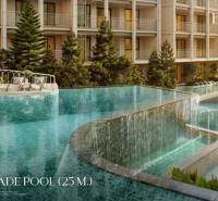 Ein Pool mit Kaskaden beim Bau von Wohnungen in Phuket mit Liegestühlen und Grünflächen.