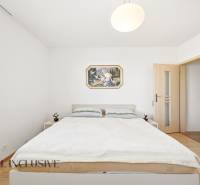 Ein Schlafzimmer in einem Einfamilienhaus mit einfacher Einrichtung und einem Boden in Holzoptik.