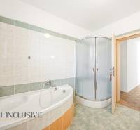 Ein Badezimmer in einem Einfamilienhaus mit Badewanne, Duschkabine und gefliesten Wänden.