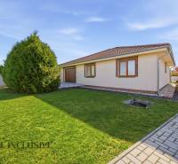 Ein Einfamilienhaus in Kútniky mit Rasen, Bäumen und Pflastersteinen.