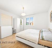 Schlafzimmer in einem Einfamilienhaus mit Holzboden, weißen Möbeln und einem Bild.