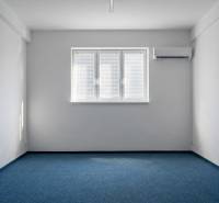 Büros mit blauem Teppichboden, weißen Wänden und Klimaanlage.