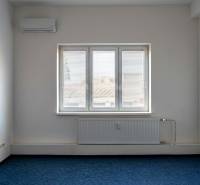 Ein Zimmer mit Klimaanlage und Fenster in Büros, blauer Teppichboden, weiße Wände.