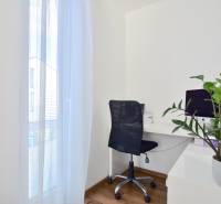 Arbeitsbereich mit Computer, schwarzem Stuhl und Pflanze auf einem Boden mit Holzdekor.