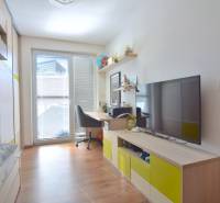 Ein Zimmer mit einem Boden in Holzoptik, einem Schreibtisch und einem Fernseher in einer 3-Zimmer-Wohnung.