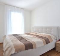Schlafzimmer mit Bett und Nachttisch in einer 3-Zimmer-Wohnung, Boden mit Holzdekor.
