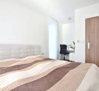 Helles Schlafzimmer mit Bett, Schreibtisch und Boden in Holzoptik in einer 3-Zimmer-Wohnung.