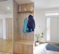 Innenraum eines Einfamilienhauses mit Holzboden und einem Spiegelschrank neben der Tür.