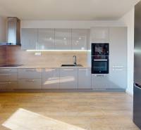 Eine Küche mit Holzboden, grauen Schränken und eingebauten Geräten in einem Einfamilienhaus.