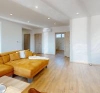 Wohnzimmer in einem Einfamilienhaus mit Holzboden und gelbem Sofa.