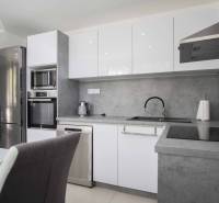 Küche in einer 2-Zimmer-Wohnung mit Edelstahlgeräten und grauer Arbeitsplatte.