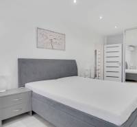 Helles Schlafzimmer mit großem Bett und Kleiderschrank in einer 2-Zimmer-Wohnung.