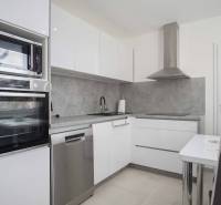 Küche in einer 2-Zimmer-Wohnung mit eingebauten Geräten und Essecke.