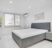 Schlafzimmer in einer 2-Zimmer-Wohnung mit großem Bett und Dekoration in gedämpften Farben.