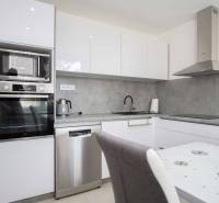 Küchenbereich einer 2-Zimmer-Wohnung mit weißen Schränken und grauer Arbeitsplatte.