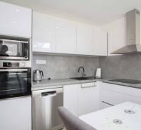 Moderne Küche mit weißen Schränken in einer 2-Zimmer-Wohnung, ausgestattet mit Geräten und Dunstabzugshaube.