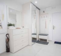 Eingangsflur mit weißen Möbeln und Spiegel in einer Zweizimmerwohnung.