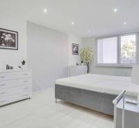 Helles Schlafzimmer in einer Zweizimmerwohnung mit weißen Möbeln und Dekorationen.