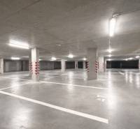Geräumige Garagen mit markierten Parkplätzen, helle Beleuchtung, Betonpfeiler.