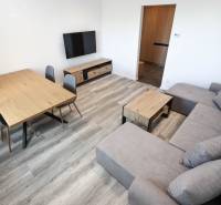Wohnzimmer in einer 3-Zimmer-Wohnung mit Holzboden, Sofa und Fernseher.