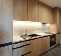 Küche mit Holzdekor, schwarzen Details, eingebauten Geräten in einer 3-Zimmer-Wohnung.