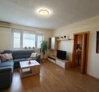 Helles Wohnzimmer mit einem blauen Sofa in einer 3-Zimmer-Wohnung, Boden mit Holzdekor.