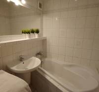 Badezimmer mit Badewanne und Waschbecken in einer 3-Zimmer-Wohnung, weiße Fliesen und Dekorationen.