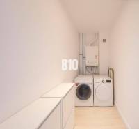 Waschmaschine, Trockner und Kessel im Waschraum einer 3-Zimmer-Wohnung mit Holzboden-Dekor.