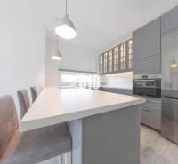 Küche in einer 3-Zimmer-Wohnung mit Insel, grauen Schränken und modernen Geräten.