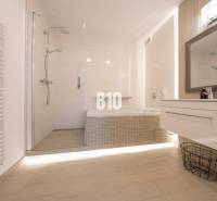 Badezimmer mit Badewanne, Dusche und Boden mit Holzdekor in einer 3-Zimmer-Wohnung.