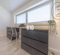 Ein Arbeitszimmer in einer 3-Zimmer-Wohnung mit Holzelementen, schwarzen Kommoden und einer Stehlampe.