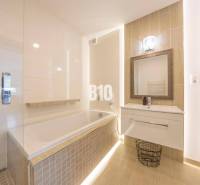 Badezimmer mit Badewanne, Waschbecken und Spiegel in einer 3-Zimmer-Wohnung mit Holzboden.