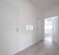 Ein heller Flur in einer 3-Zimmer-Wohnung mit einem Boden in Holzoptik und weißen Türen.