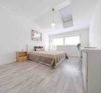 Helles Schlafzimmer mit großem Bett, Fenster und Holzboden in einer 3-Zimmer-Wohnung.