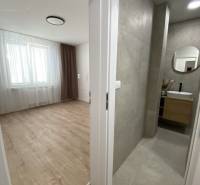 Ein Zimmer mit Holzboden neben dem Badezimmer in einer Zweizimmerwohnung.