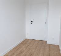 Ein Zimmer in einer 3-Zimmer-Wohnung mit weißen Wänden und einem Boden in Holzoptik.
