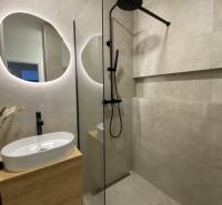 Badezimmer mit Waschbecken, Duschkabine und Spiegel in einer 3-Zimmer-Wohnung.