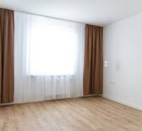 Ein Zimmer in einer 3-Zimmer-Wohnung mit braunen Vorhängen und einem Boden in Holzoptik.