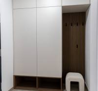 Ein eingebauter weißer Schrank mit offenen Regalen und einem Stuhl in einer 2-Zimmer-Wohnung.