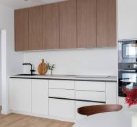Küche in einer 2-Zimmer-Wohnung mit weißen Schränken und einem Boden in Holzoptik.