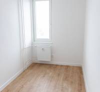 Ein Zimmer in einer 3-Zimmer-Wohnung mit einem Fenster und einem Boden in Holzoptik.
