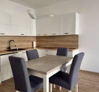 Küche in einer 2-Zimmer-Wohnung mit weißen Schränken und einem Boden in Holzoptik.
