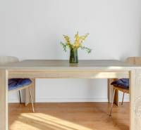 Ein Esstisch mit einer Blumenvase auf dem Boden mit Holzdekor in einer 2-Zimmer-Wohnung.