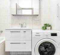 Badezimmer mit Badewanne, Waschbecken und Waschmaschine in einer 2-Zimmer-Wohnung.