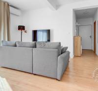 Helles Wohnzimmer mit Holzdekorboden und grauem Sofa in einer Zweizimmerwohnung.