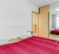 Schlafzimmer in einer 2-Zimmer-Wohnung mit einem großen Spiegelschrank und einem Boden in Holzoptik.